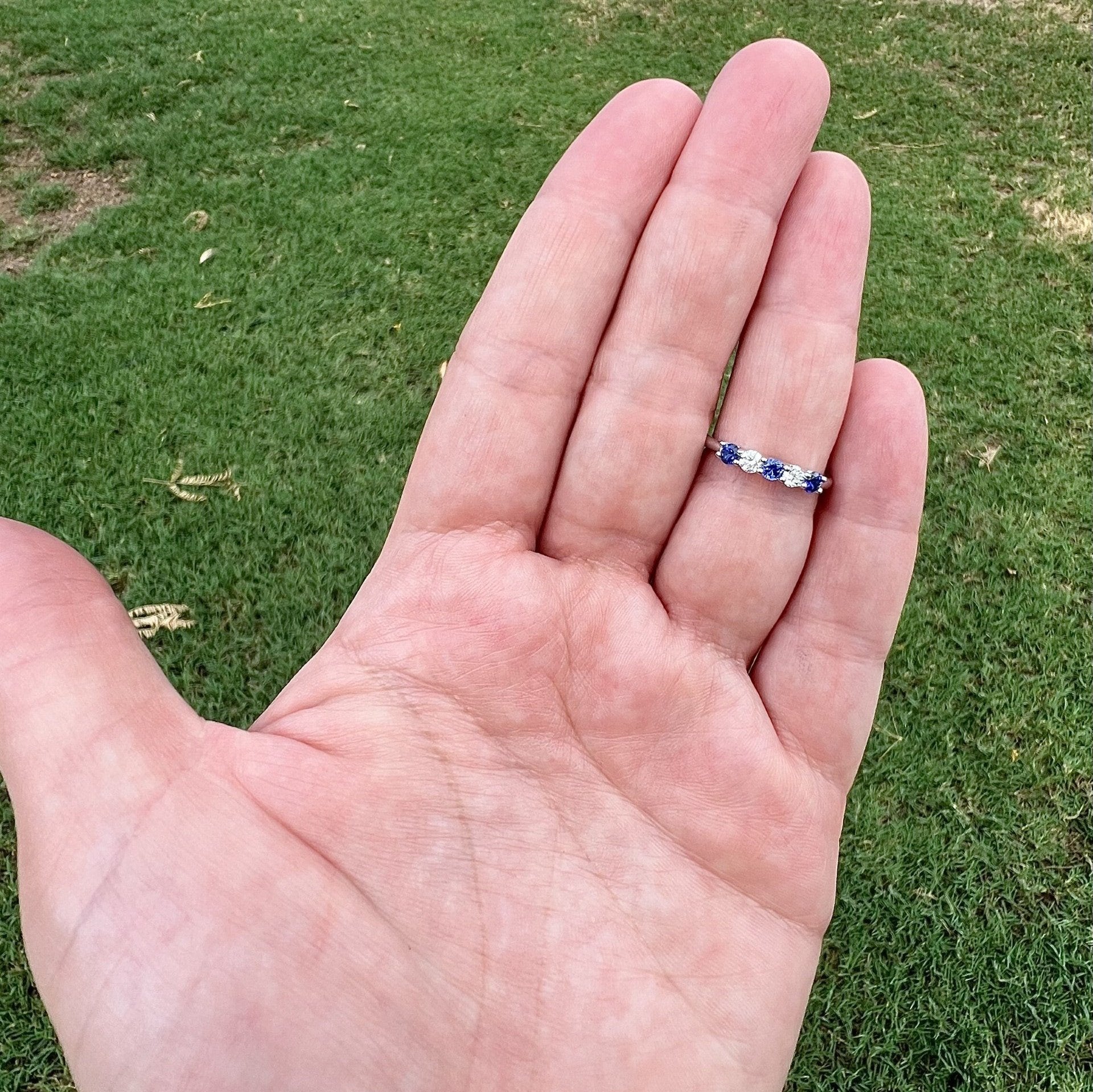 Alternation blue sapphire and diamond 5 stone ring band set in 14k white gold placed on ring finger for size reference
