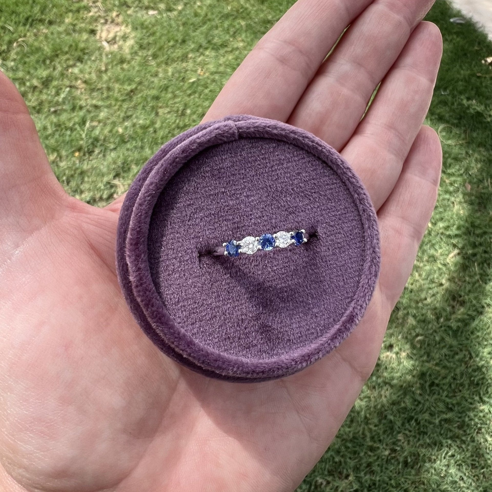 Angle view of alternating round blue sapphire and diamond ring band with 5 stones total set in 14k white gold