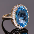 oval blue topaz ring with white sapphire halo in yellow gold