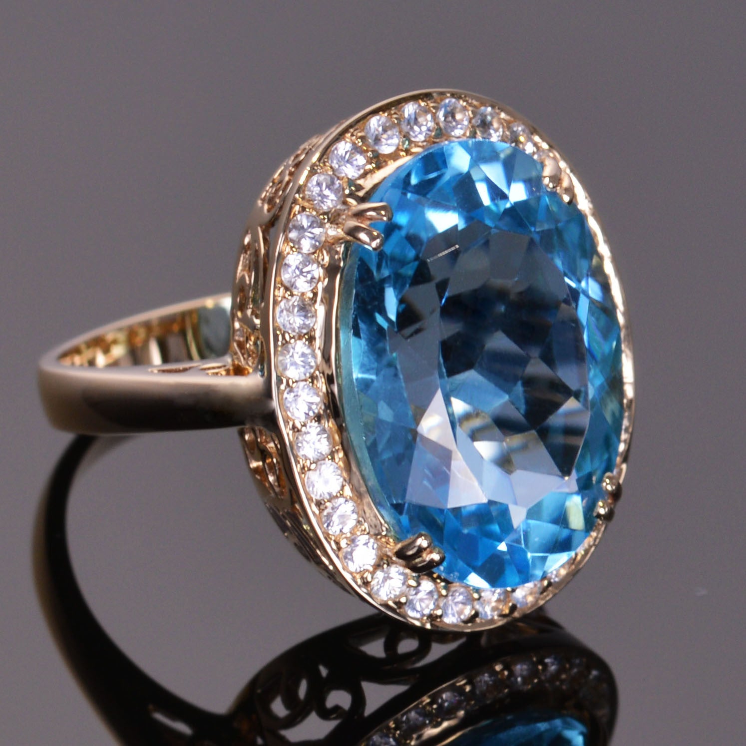 oval blue topaz ring with white sapphire halo in yellow gold